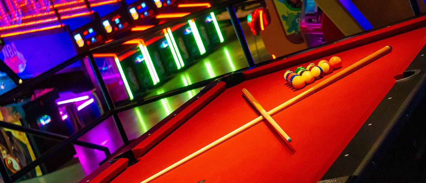 Billiard Table with arcade games in background